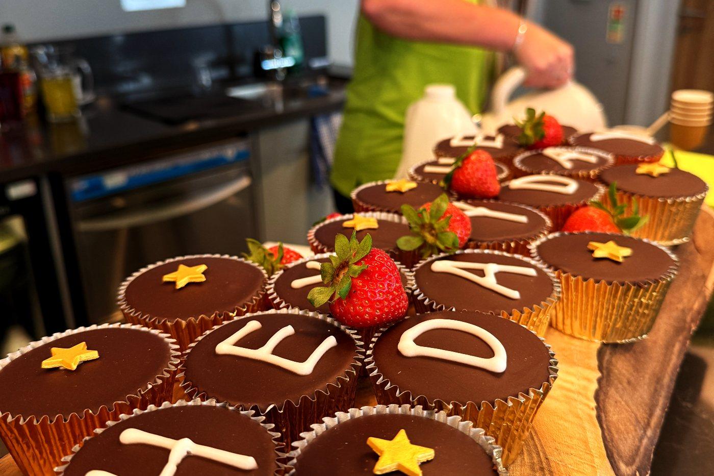 Chocolate cupcakes iced with the letters of Heyday, with strawberries